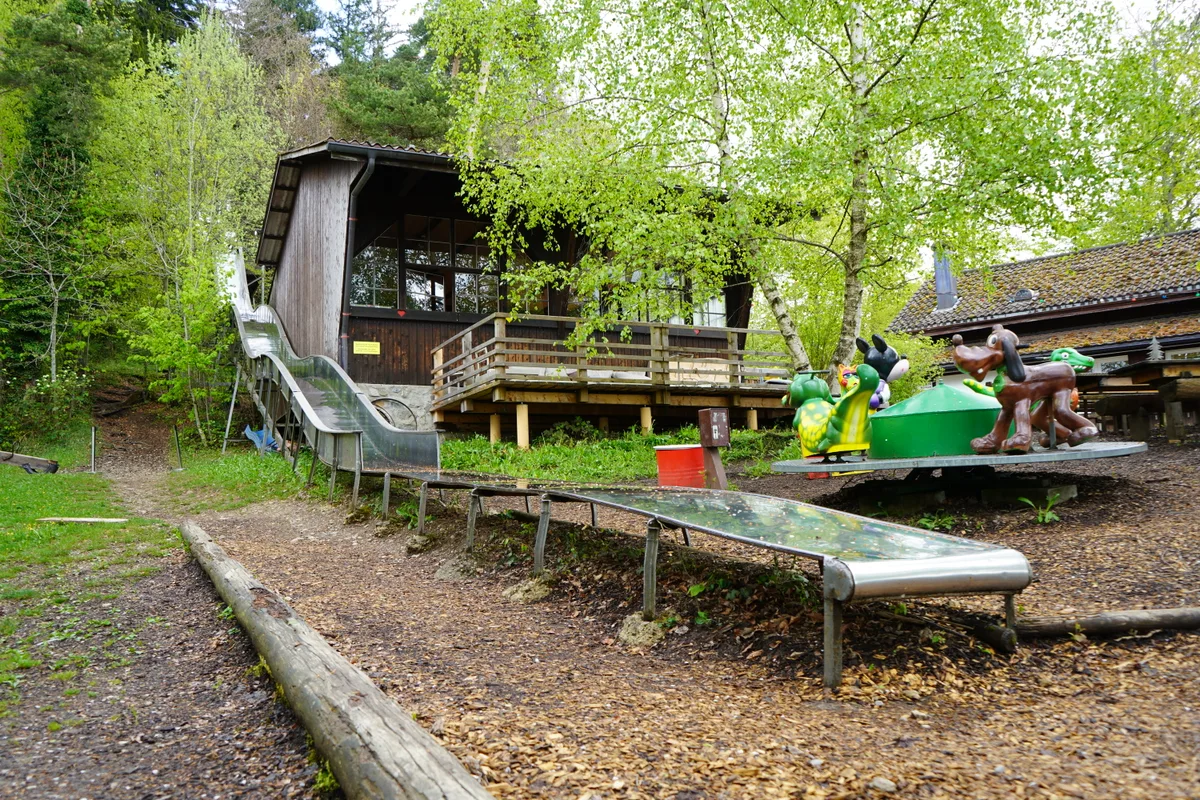 Ein Gebäude auf dem Berg, zwischen den Bäumen liegt ein ziemlich bemerkenswerter Spielplatz.